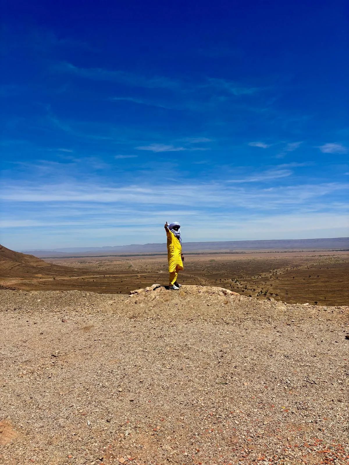 Persona con chaqueta amarilla en una meseta de piedra bajo un cielo azul