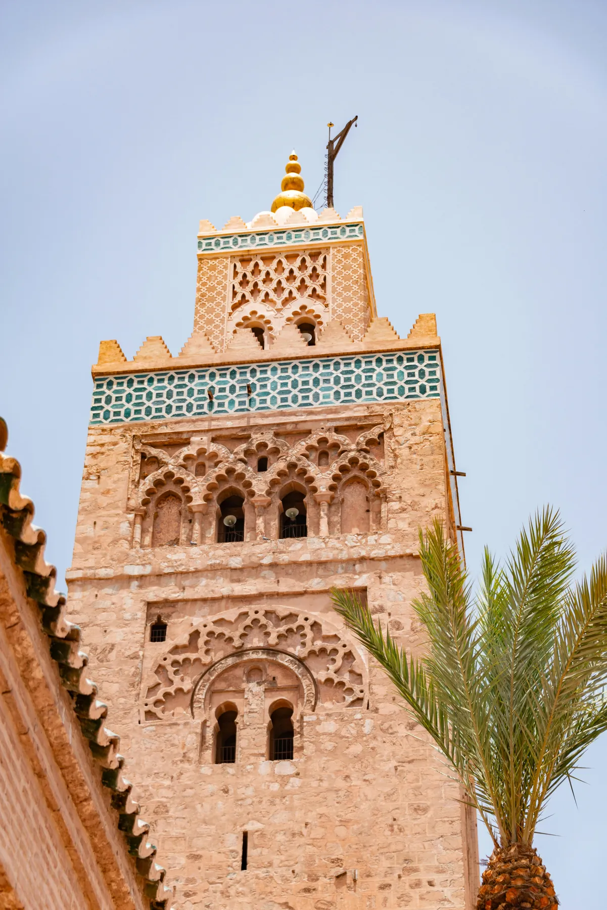 Torre de una mezquita con palmera en Marrakech