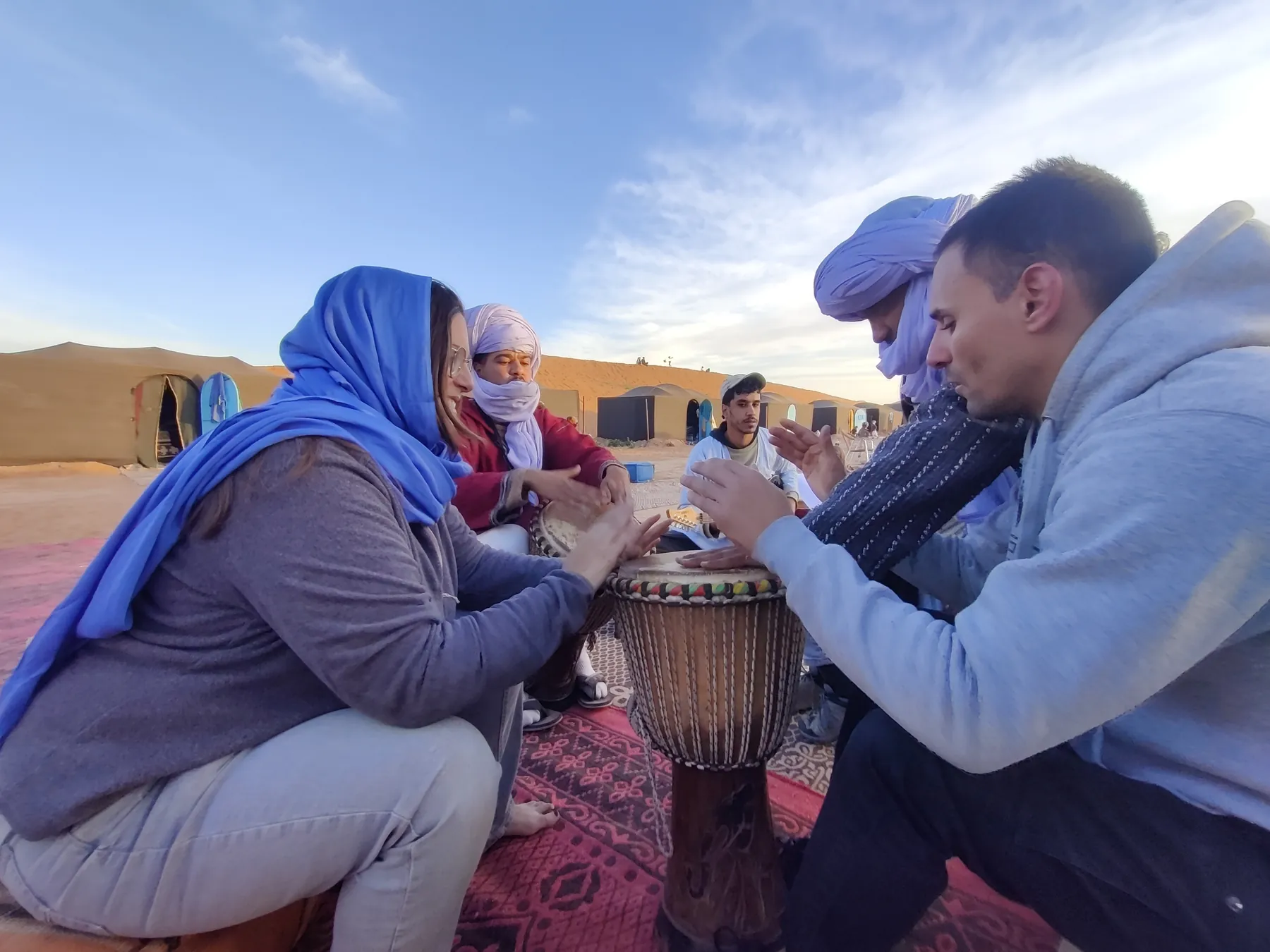 Viajeros y guías tocando un tambor en el campamento